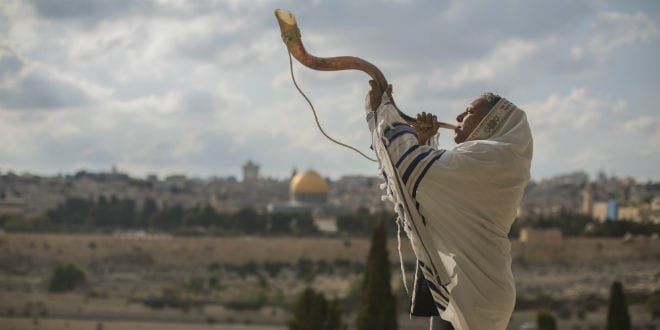 A man blows a  shofar. The Temple Mount in Jerusalem's Old City can be seen in the background. (Photo: Yonatan Sindel/Flash90 )